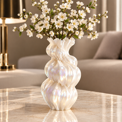 Pearl white tiered sculptural vase with white flowering branches on a marble-look table.